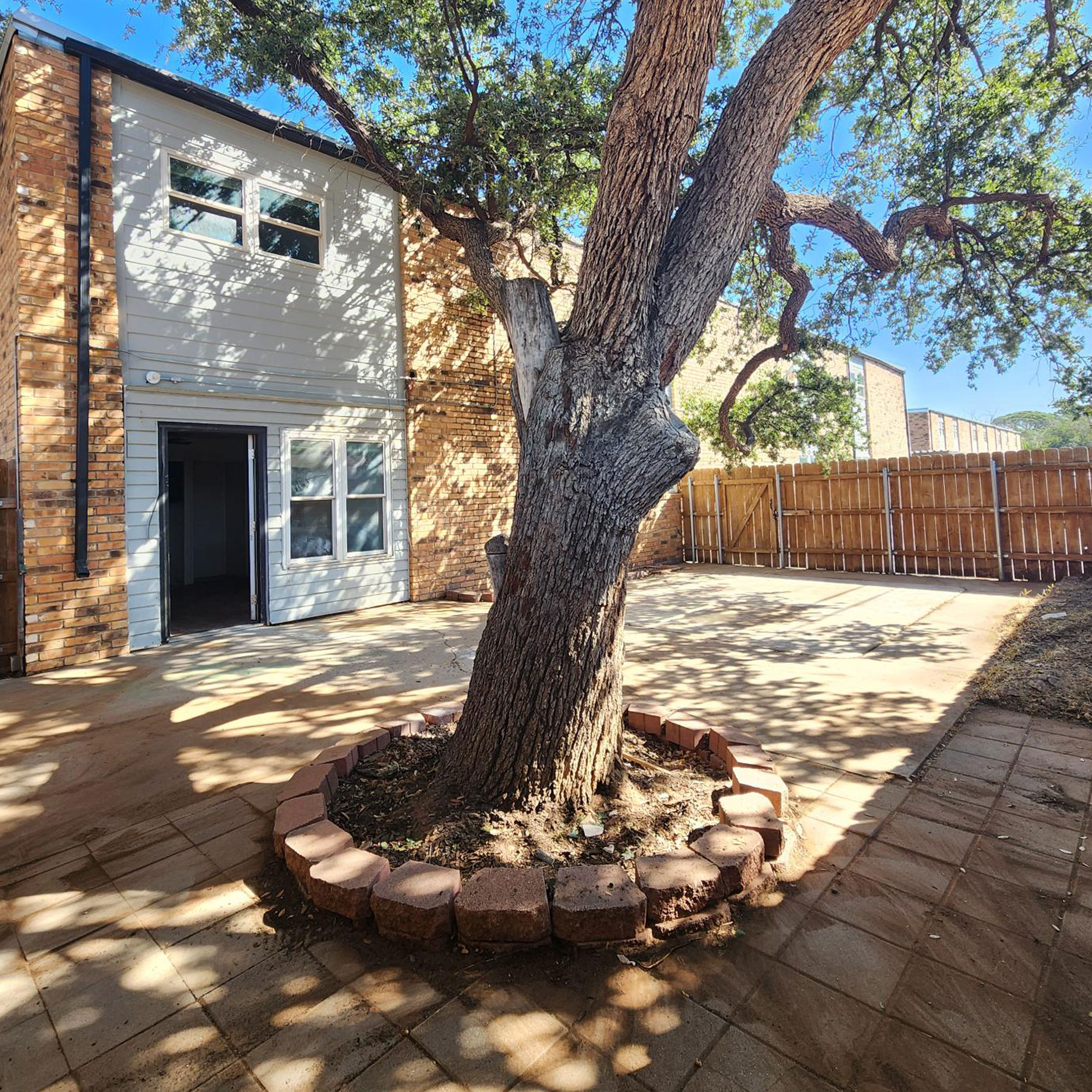 Fenced private backyard with a patio shaded by a mature tree